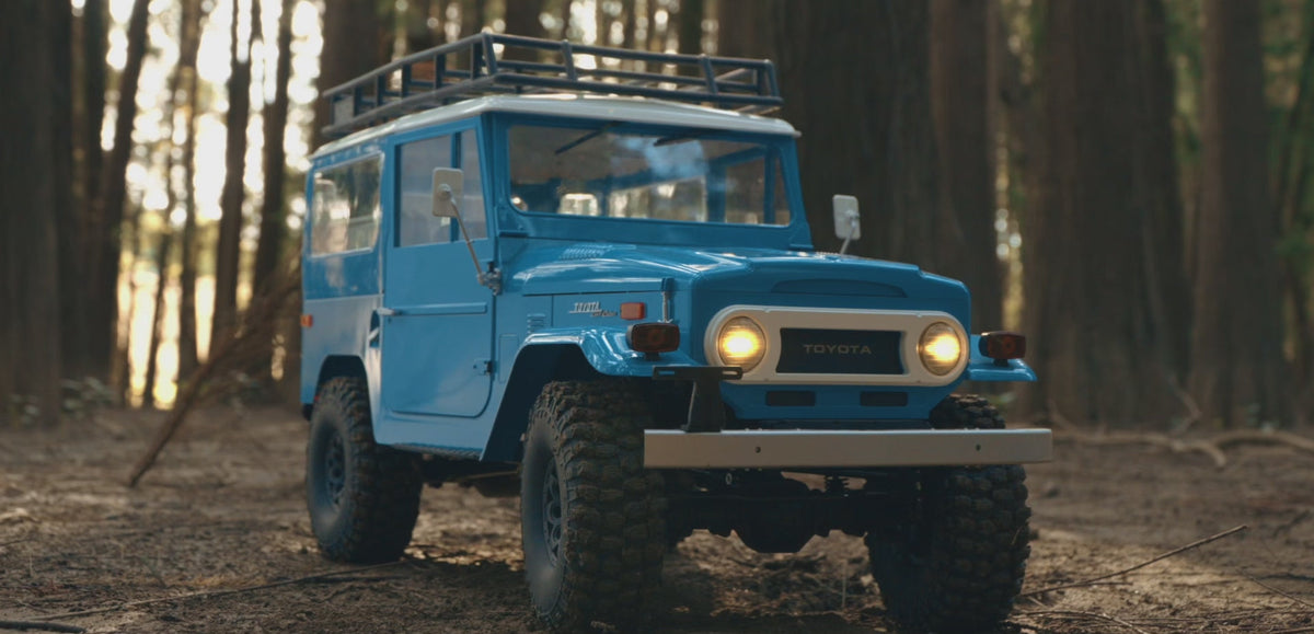 Blue FMS Toyota Land Cruiser FJ40 1/10 crawler on a rocky trail
