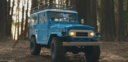 Blue FMS Toyota Land Cruiser FJ40 1/10 crawler on a rocky trail